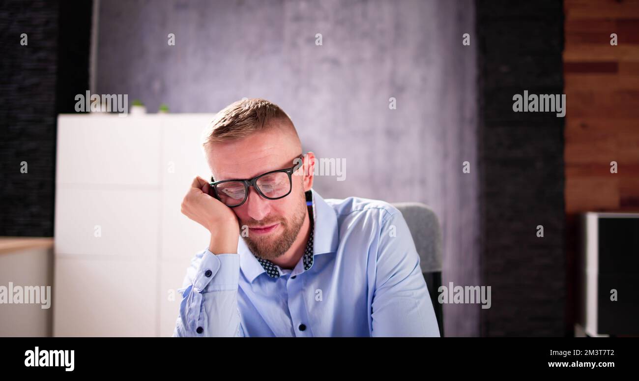 Deprimierter, Trauriger Mann Mit Kopfschmerzen, Der Im Büro Sitzt Stockfoto