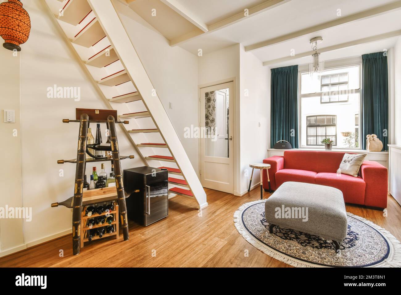 Ein Wohnzimmer mit einer roten Couch und Treppen, die in die oberste Etage vor den Treppen führen Stockfoto