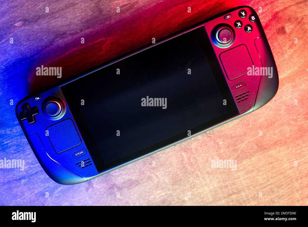 Lublin, Polen. 16. Dezember 2022 Valve Steam Deck Spielkonsole auf Holztisch, beleuchtet mit modernen roten und blauen LED-Lichtern Stockfoto