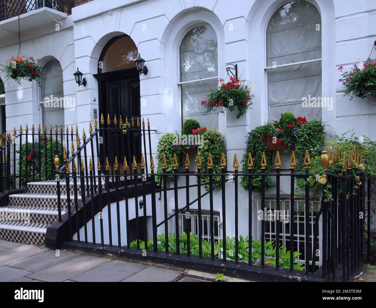 Eintritt zum typischen weiß bemalten Londoner Stadthaus, mit hängenden Körben mit Sommerblumen Stockfoto