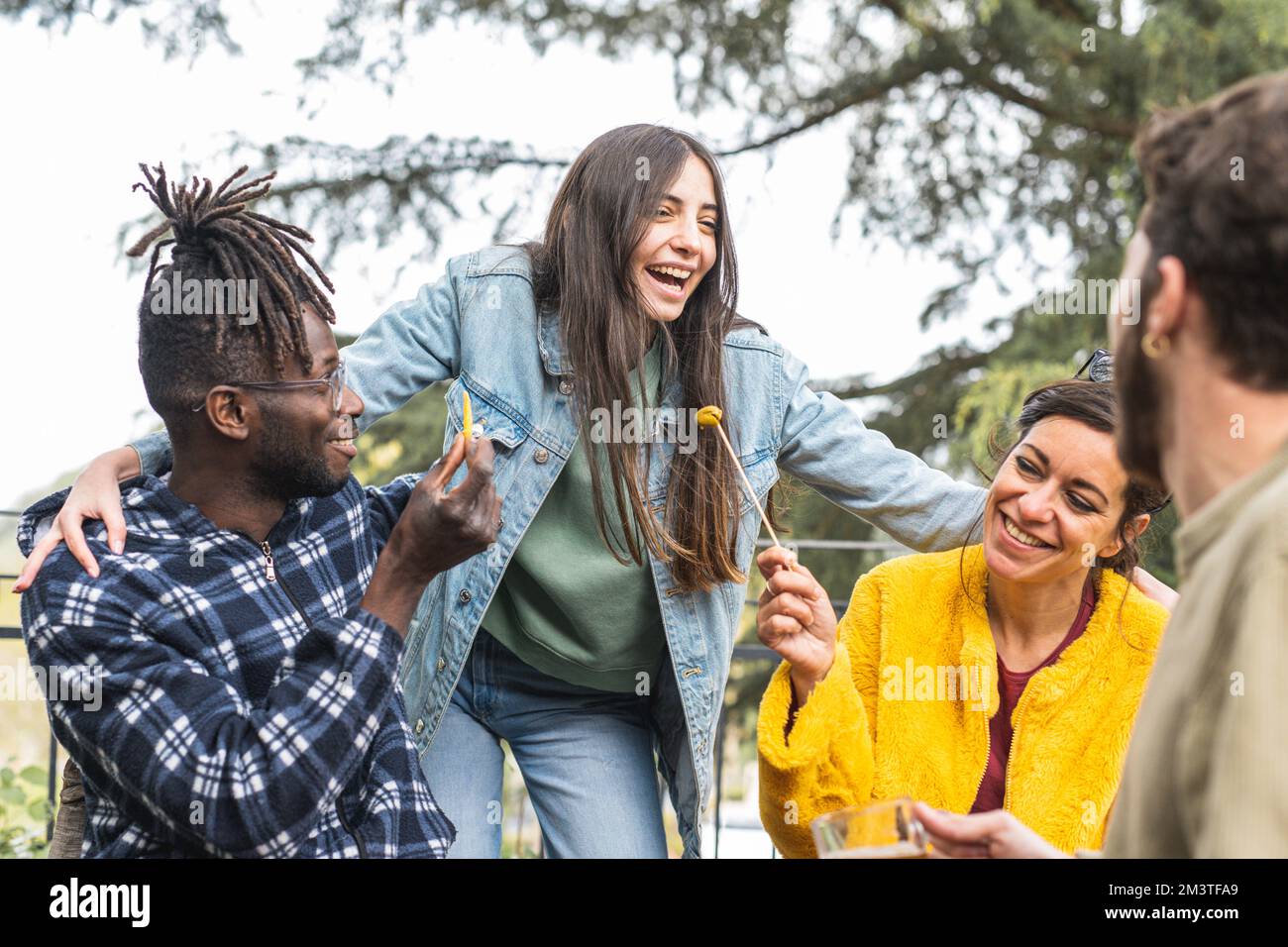 Leute, die draußen über die Happy Hour lachen, eine Gruppe von multirassischen Freunden, die Spaß auf einer Party haben, junger Erwachsener Stockfoto