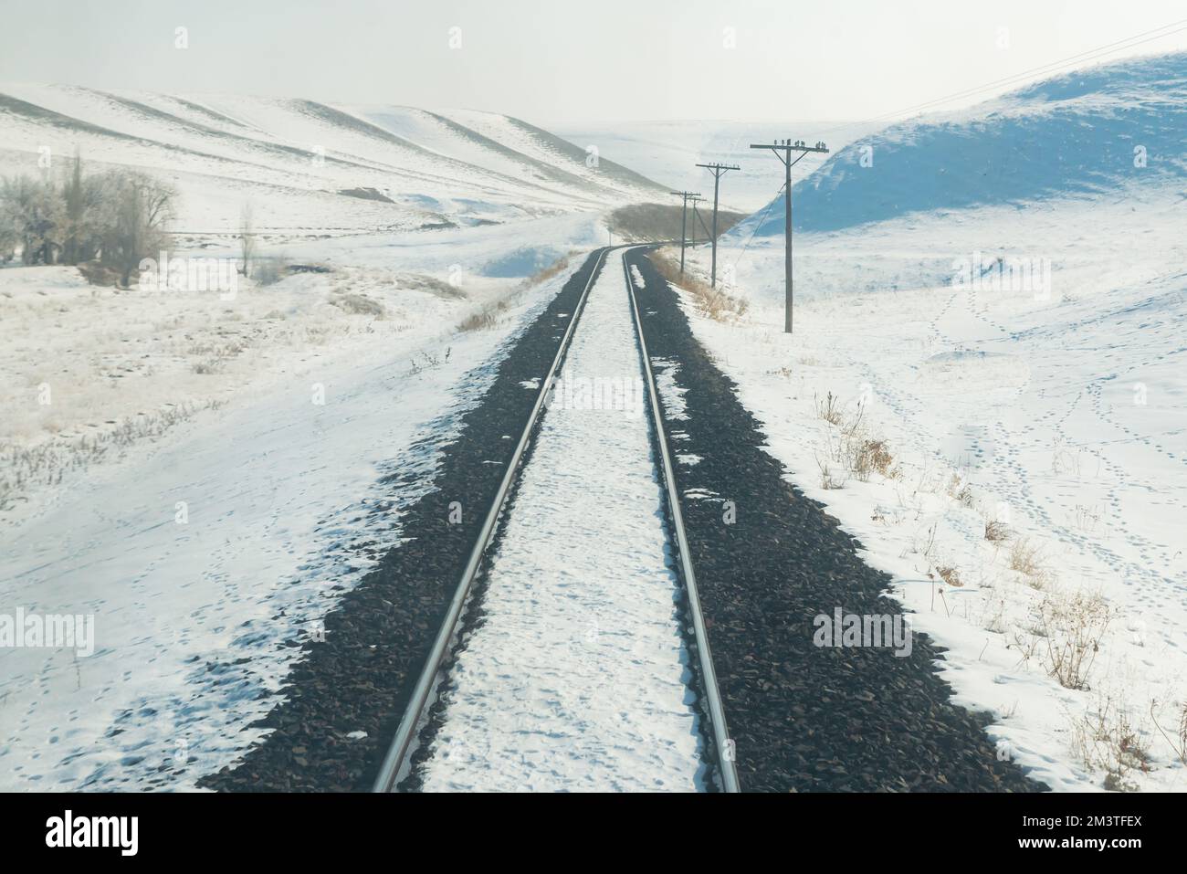 Wintersaison und Zugfahrt, Zuggleise von der Rückseite des Zuges und verschneites Hintergrundfoto Stockfoto