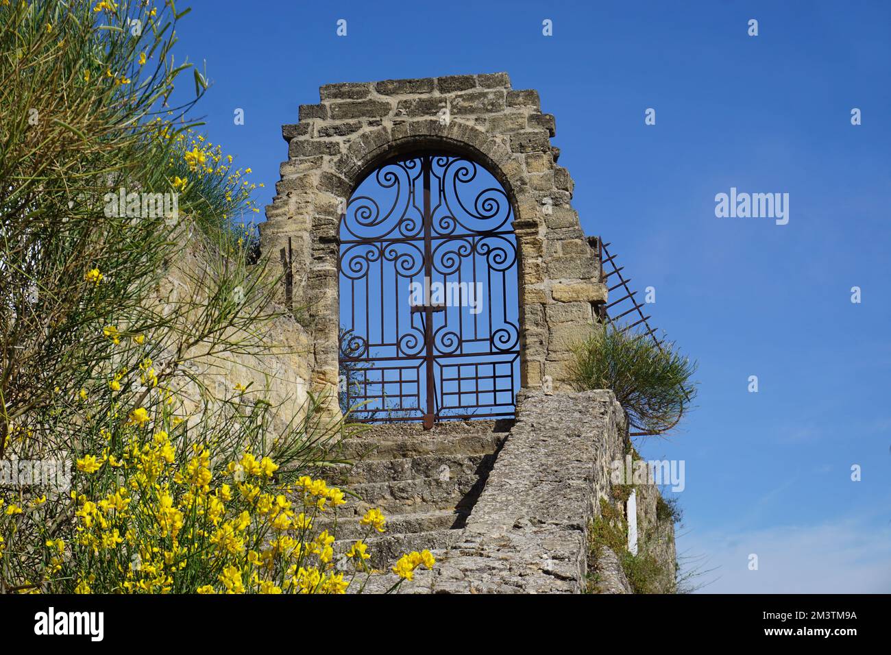 Landschaft in den südlichen Hügeln der alpen, Frankreich im Frühling an einem sonnigen Tag mit einer eisernen Werkstür auf einem alten Steinwandbogen Stockfoto