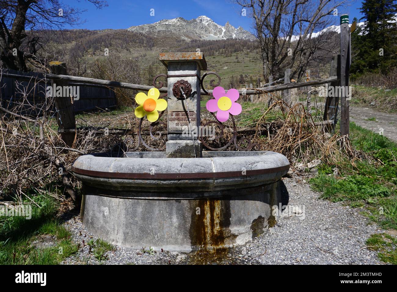 Landschaft in den Bergen der südlichen alpen, Frankreich mit einem alten Steinbrunnen, dekoriert mit metallbemalten Blumen Stockfoto