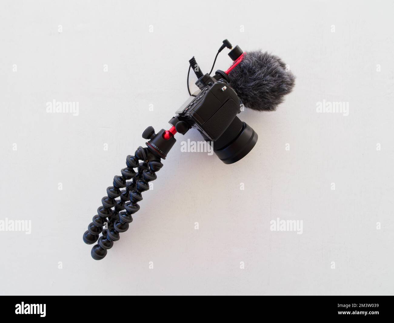 Digitalkamera mit Mikrofon und Stativ auf Weiß. Vlogging-Konzept. Stockfoto