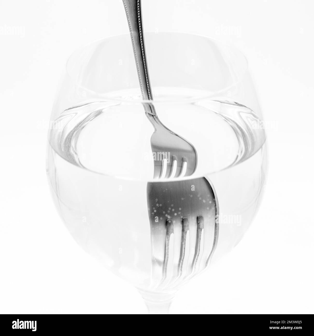 Vista de un tenedor distorsionado dentro de una vaso lleno de agua, demostrando la refracción de la luz Stockfoto