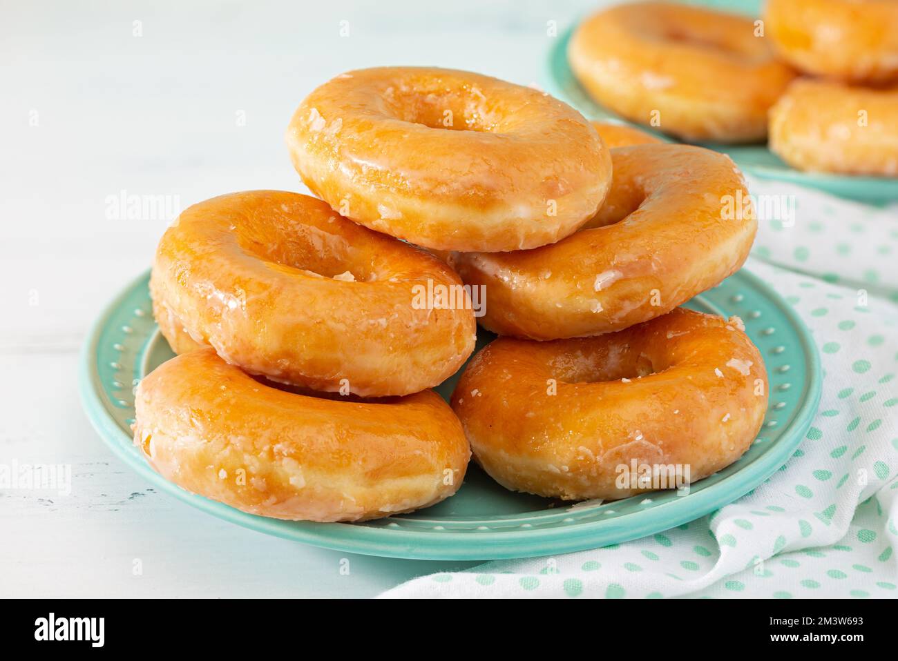 Glasierte Donuts auf einem aquafarbenen Teller mit passender Bettwäsche; Kopierbereich Stockfoto