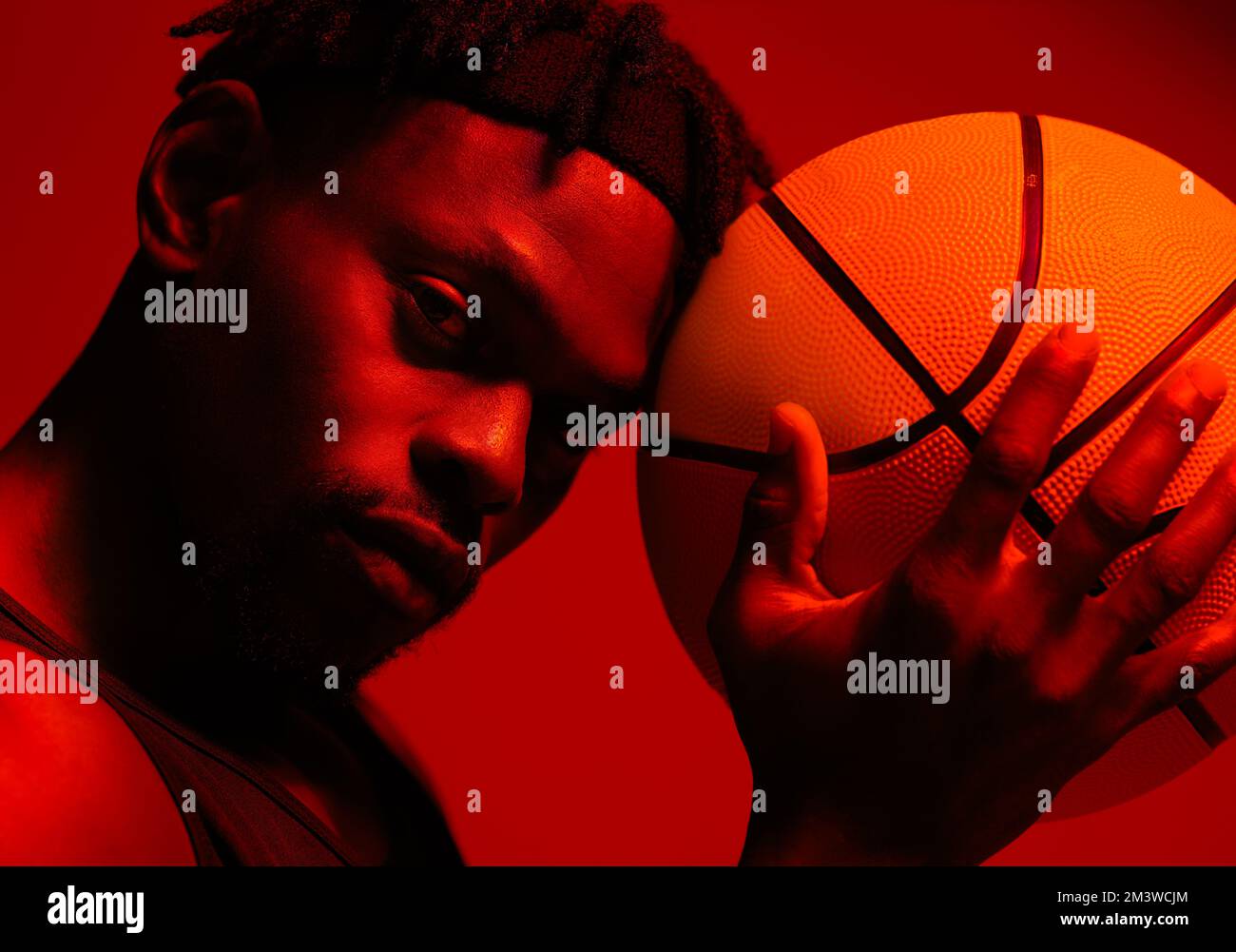 Ich habe das Spiel nie aufgegeben. Rot gefilterte Aufnahme eines jungen Sportlers, der mit einem Basketball im Studio posiert. Stockfoto
