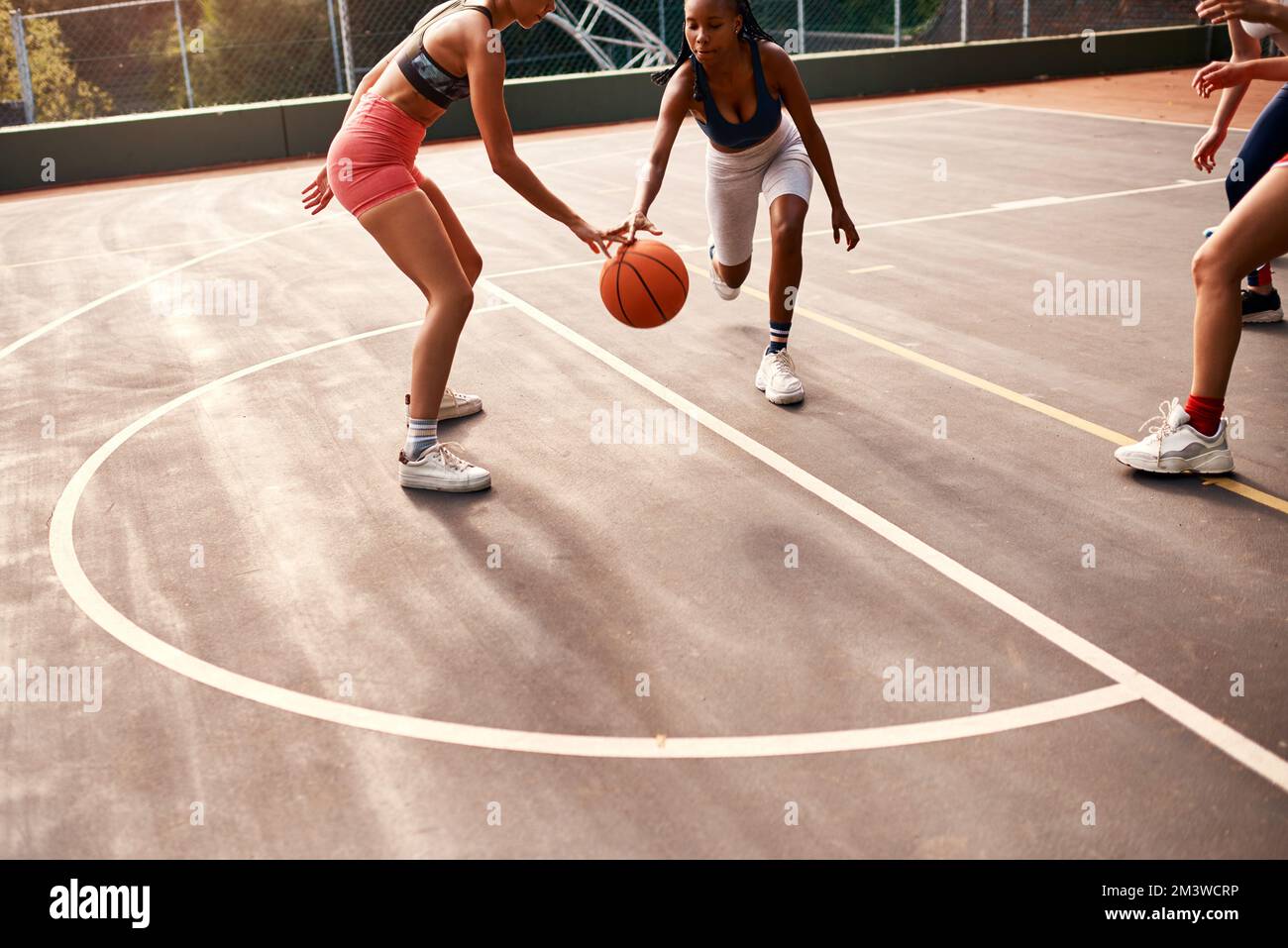 Immer den Ball schützen. Eine vielfältige Gruppe von Sportlerinnen, die tagsüber gemeinsam ein Wettkampfspiel mit Basketball spielen. Stockfoto