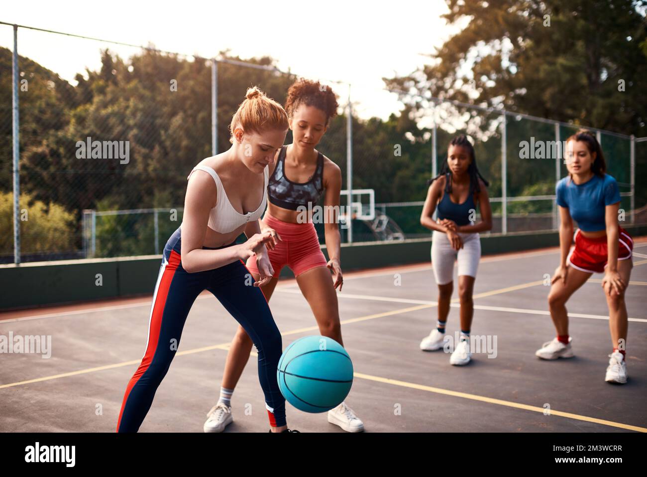 Das ist ein Wettkampfsport. Eine vielfältige Gruppe von Sportlerinnen, die tagsüber gemeinsam ein Wettkampfspiel mit Basketball spielen. Stockfoto