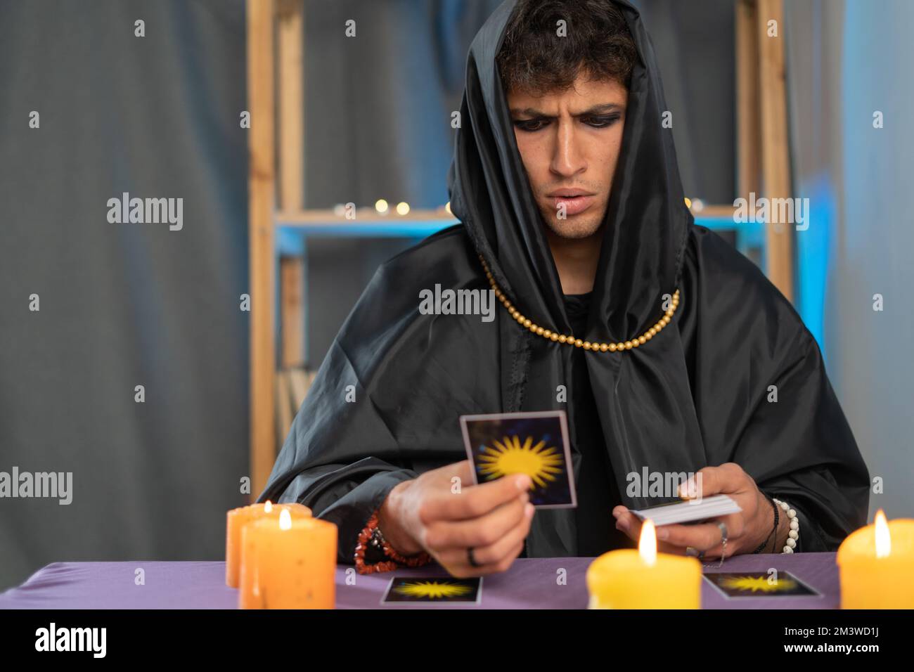 Ein Wahrsager, der Tarot-Karten auf einem Tisch mit Kerzen liest. Stockfoto