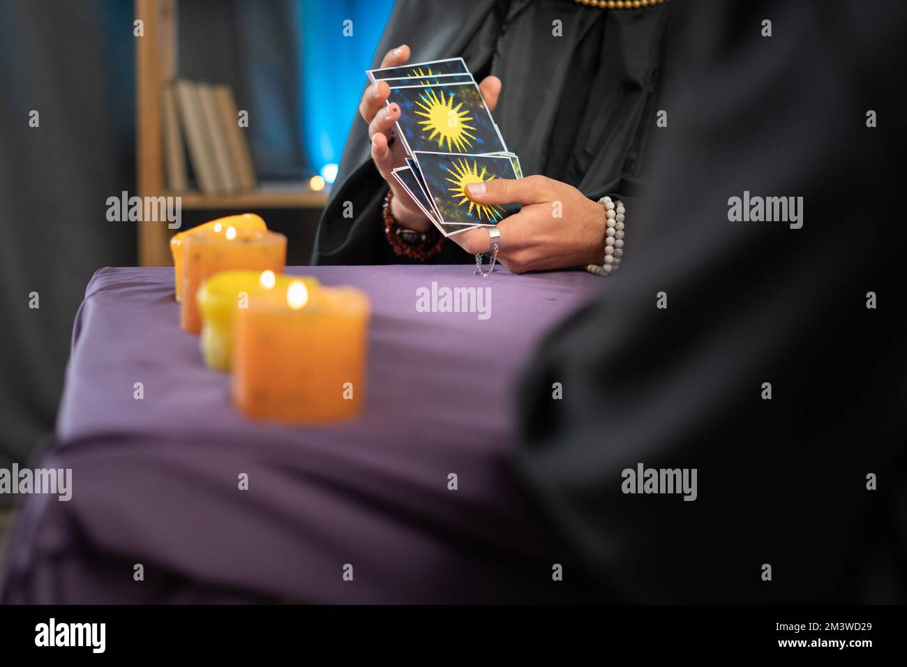 Nahaufnahme einer Hand eines Wahrsagers, die Tarotkarten über einem Tisch mit Kerzen hält, eine zukünftige Vorhersage für einen Kunden Stockfoto