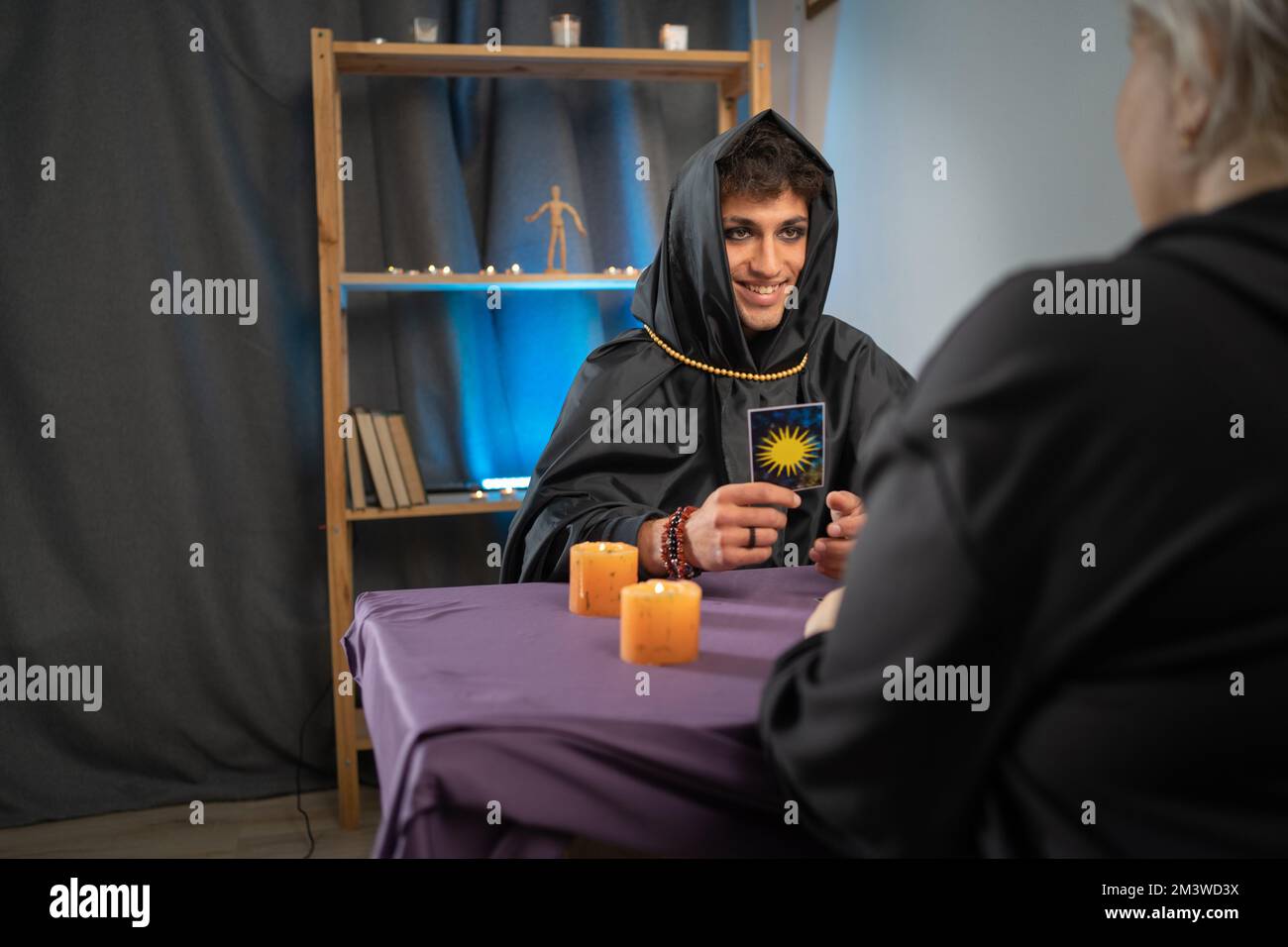 Man-Wahrsager in Zauberkostüm mit Make-up-Lesekarten, Enthüllungsprognose der Zukunft für den Kunden, neue Geschäfte Stockfoto