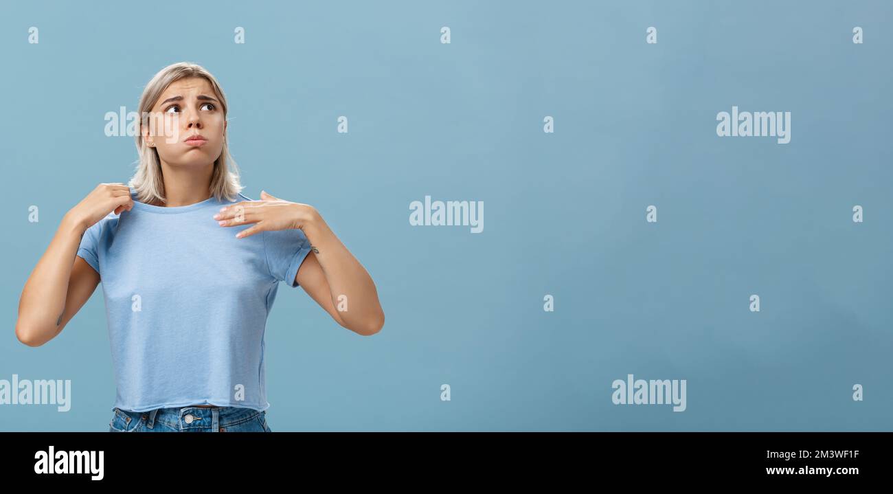 Mädchen Gefühl Unbehagen von Hitze stehen über blauem Hintergrund in fug atmete aus und runzelte die Stirn und schaute auf die leidende Sonne Von heißem Wetter winken Stockfoto