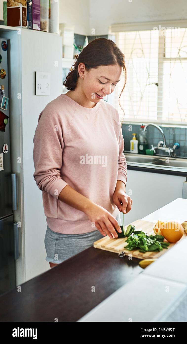 Beginnen Sie jetzt gesund zu essen. Eine junge Frau, die zu Hause in der Küche Gemüse hackt. Stockfoto