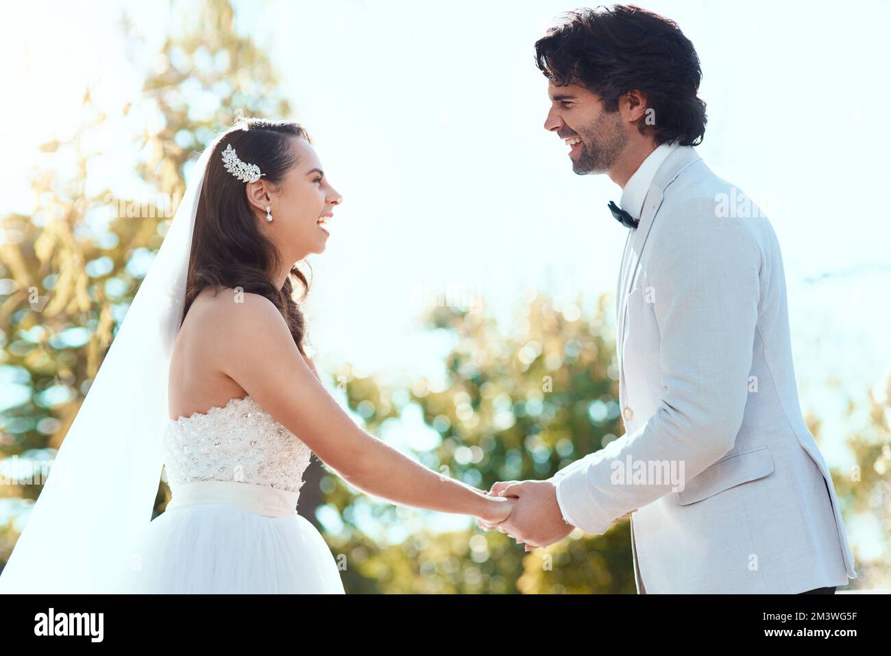 Verheiratet mit dem Glück. Ein liebevolles junges Paar, das sich anlächelt, während es an seinem Hochzeitstag Händchen hält. Stockfoto