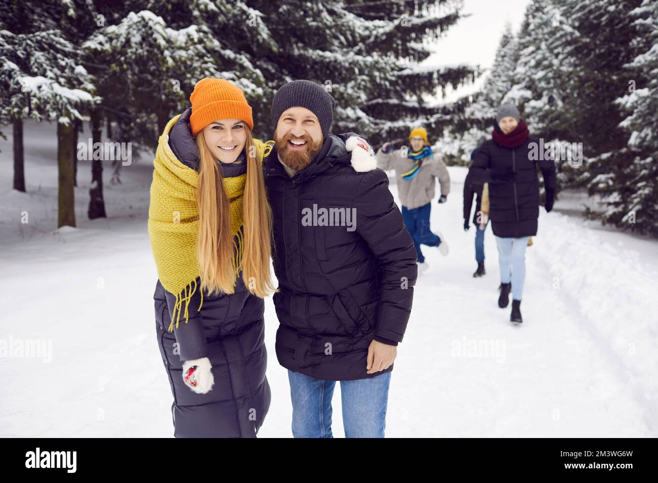 Portrait eines lächelnden glücklichen Paares mit Freunden auf einem Winterspaziergang im verschneiten Wald. Stockfoto
