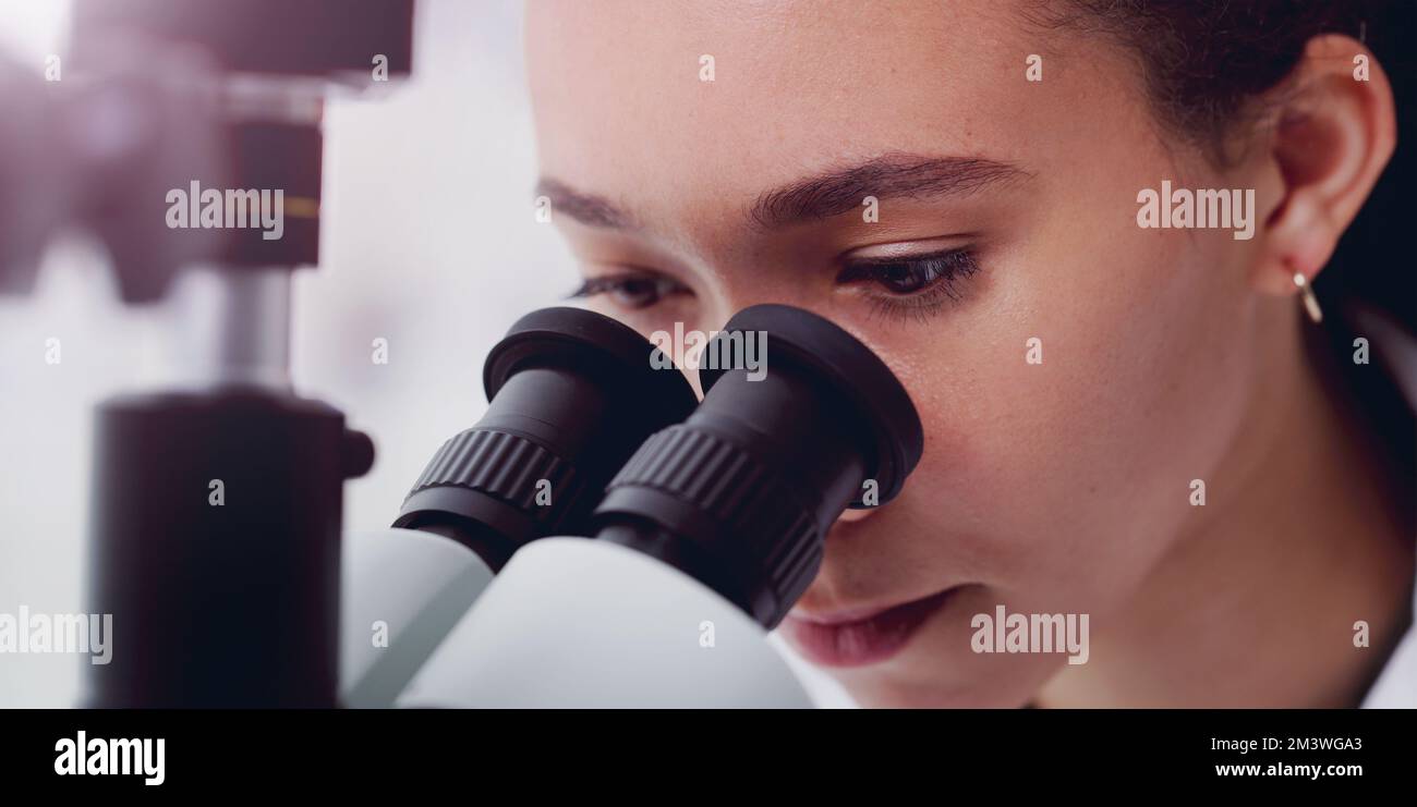 Was haben wir denn hier? Ein junger Wissenschaftler, der ein Mikroskop in einem Labor benutzt. Stockfoto