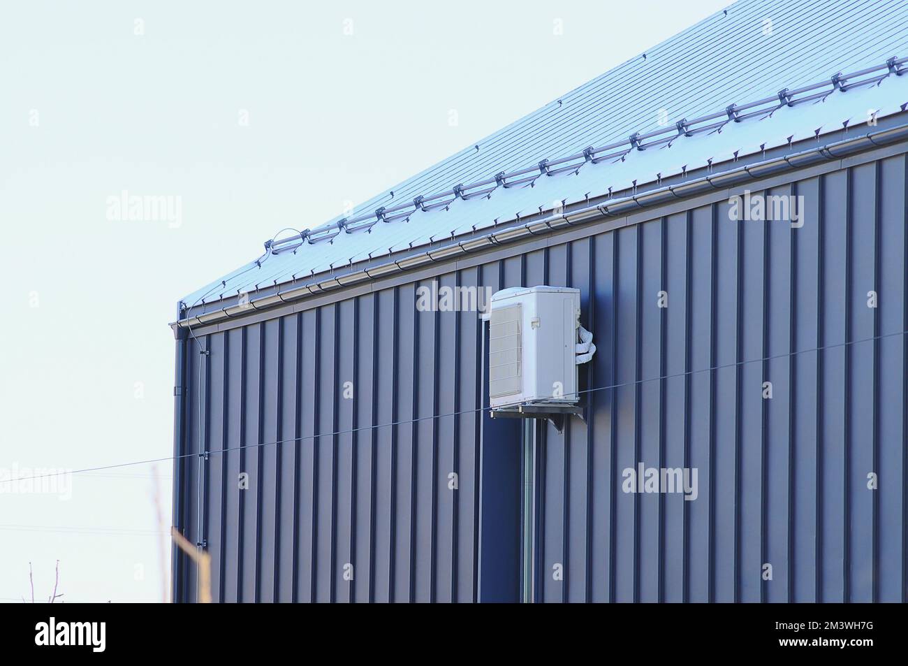 Eine externe Klimaanlage an der Fassade des Hauses im Winter. Die Fassade der Metallverkleidung ist schwarz Stockfoto