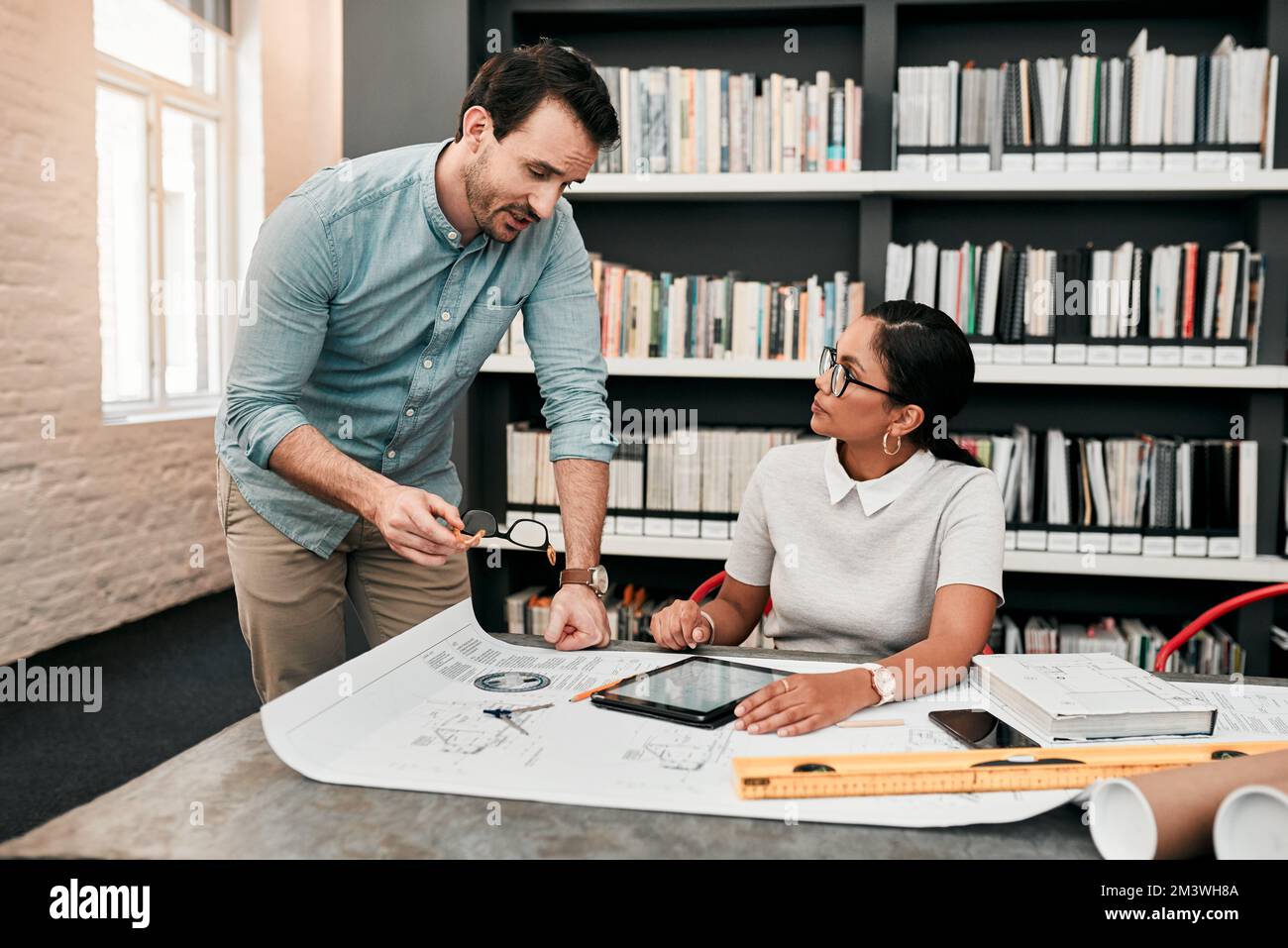 Ich dachte, wir könnten die Dinge anders angehen... zwei aufstrebende junge Architekten, die ein digitales Tablet verwenden, während sie in einem modernen Büro zusammenarbeiten. Stockfoto