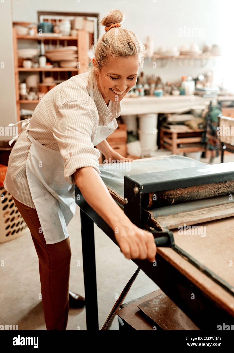 Du würdest auch lächeln, wenn du Töpfer wärst. Eine Kunsthandwerkerin, die in ihrer Töpferwerkstatt arbeitet. Stockfoto