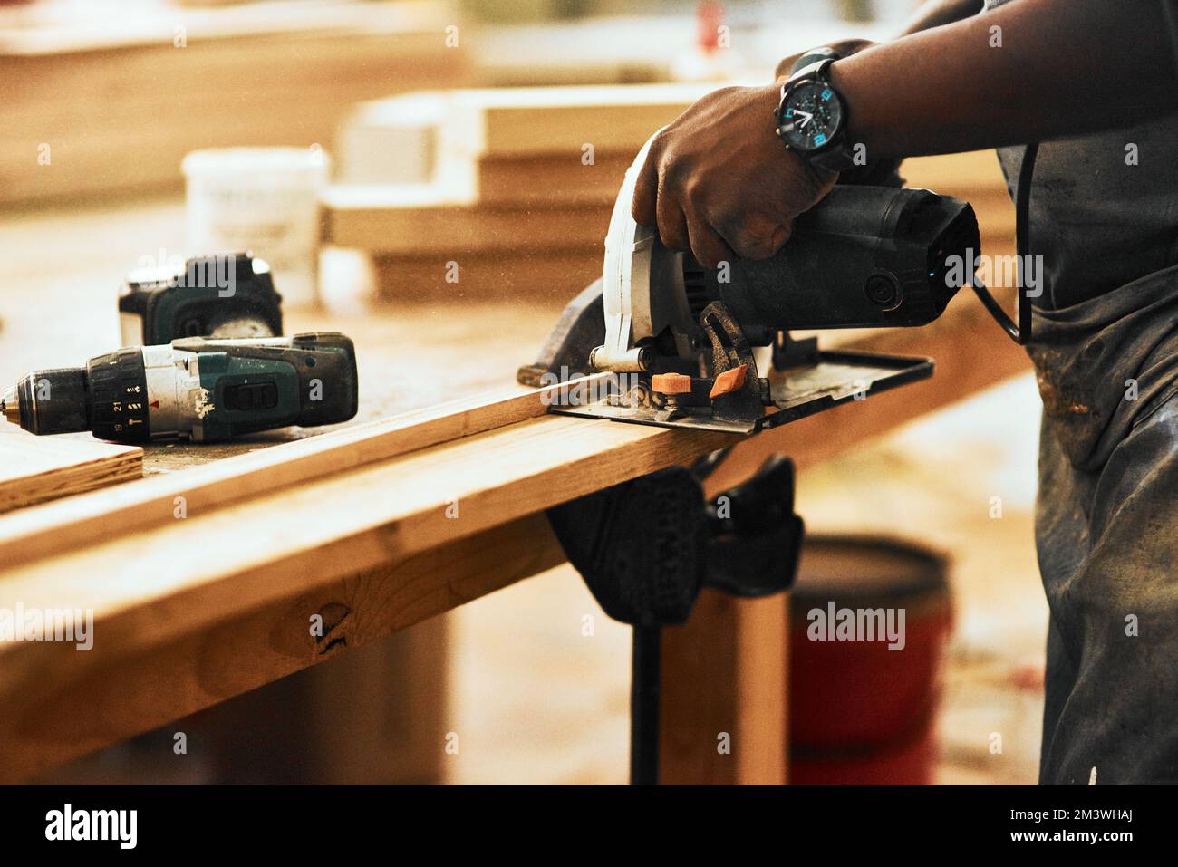 Elektrowerkzeuge tragen zur Steigerung der Produktivität in Ihrer Werkstatt bei. Ein unerkannter Zimmermann, der mit einer Kreissäge Holz in einer Werkstatt schneidet. Stockfoto