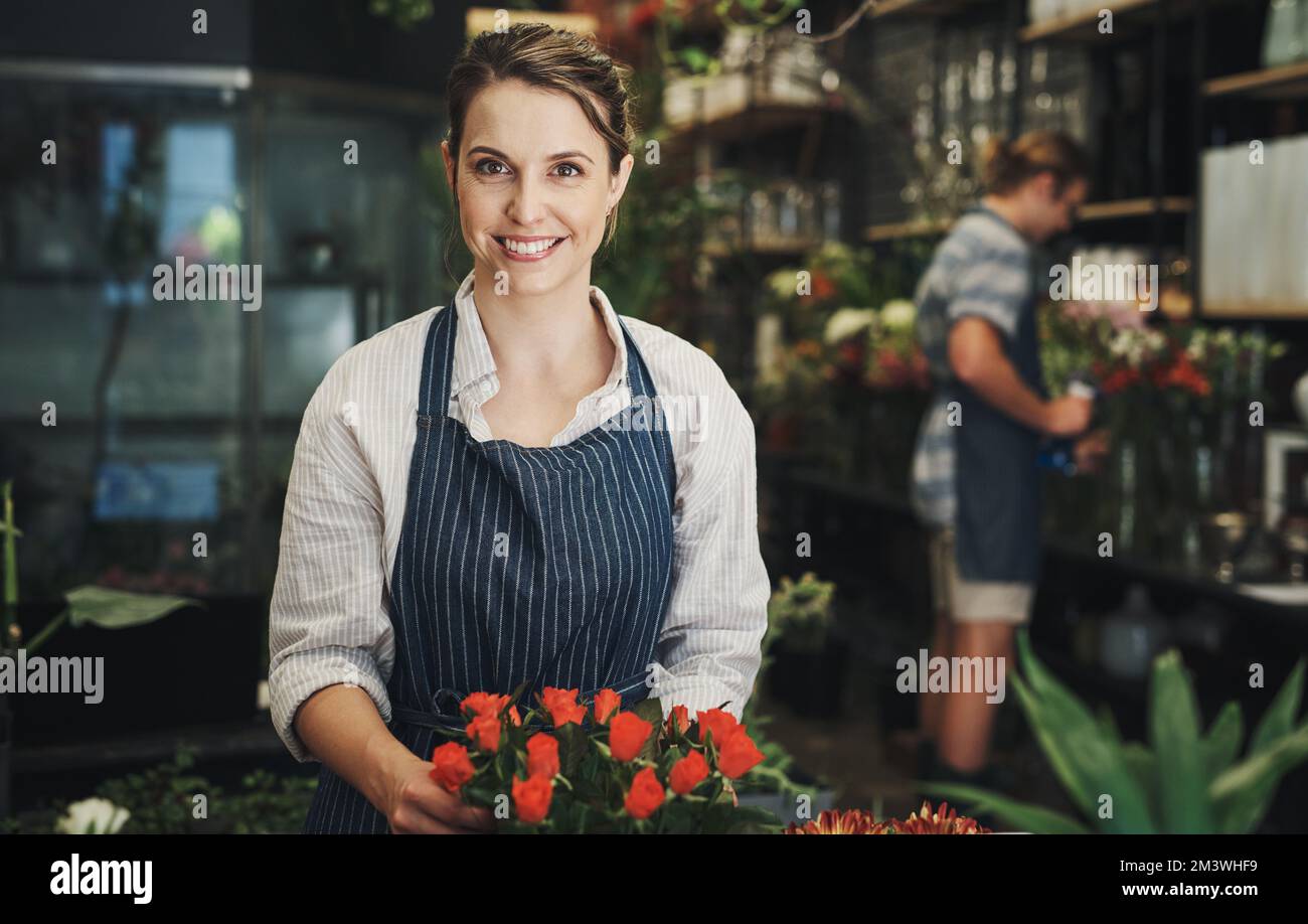 Blumen erwecken Farbe und Glück zum Leben. Porträt einer attraktiven jungen Floristin, die mit ihrer Kollegin Blumen in einer Baumschule arrangiert Stockfoto