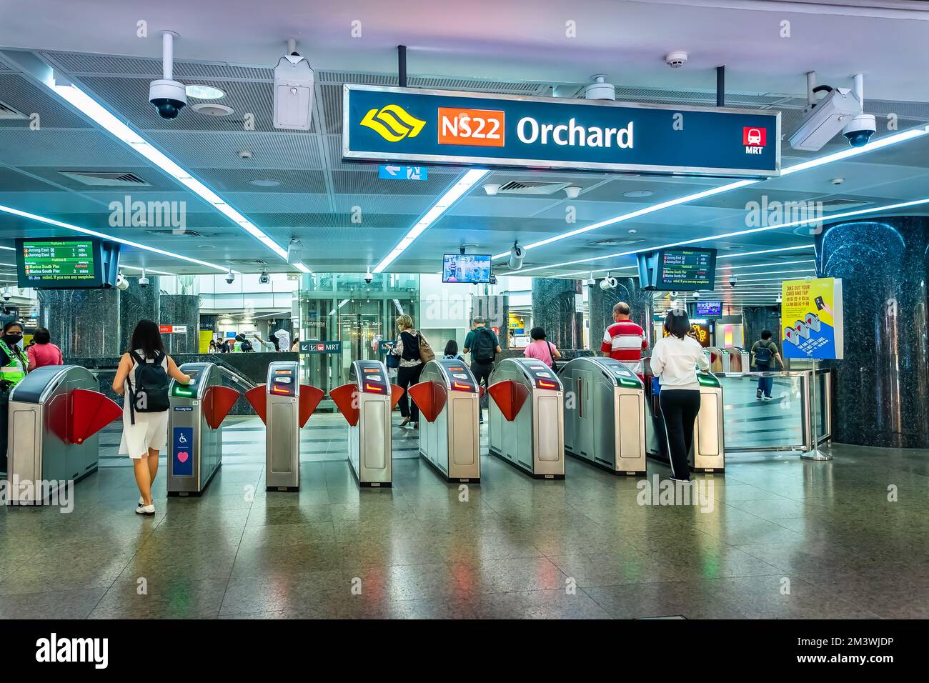 Passagiere, die an den Gates der automatischen Fare Collection am MRT-Bahnhof Orchard einchecken. Stockfoto