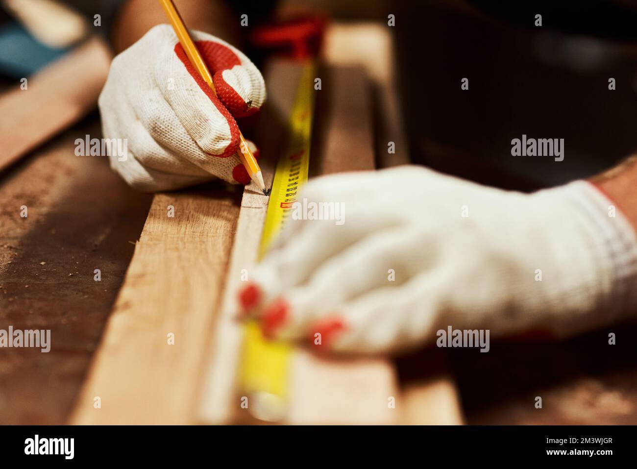 Nur eine kleine Markierung. Nahaufnahme eines unbekannten Zimmermanns, der nachts Messungen an einem Stück Holz in einer Werkstatt vornimmt. Stockfoto