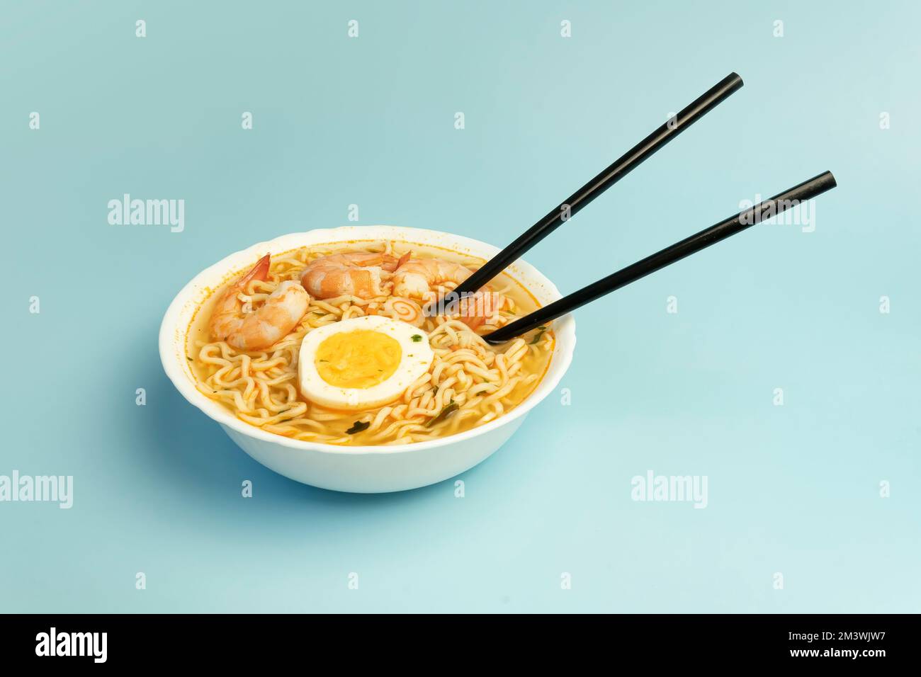 Würzige Suppe nach Thai-Art und Nudeln garniert mit Garnelen, genannt Tom Yum Goong auf weißer Schüssel mit Stäbchen, hergestellt mit Mama-Nudelgarnelen und Chili, heiß Stockfoto