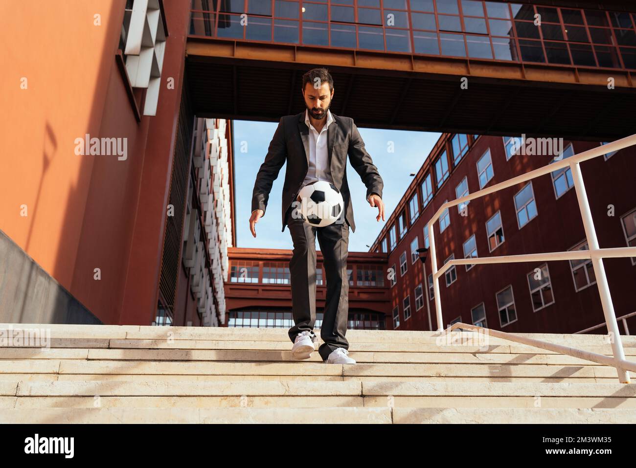 Bild eines Geschäftsmanns und Freispielers, der mit dem Ball auf der Straße Tricks macht. Konzept über Sport- und Geschäftsleute Stockfoto