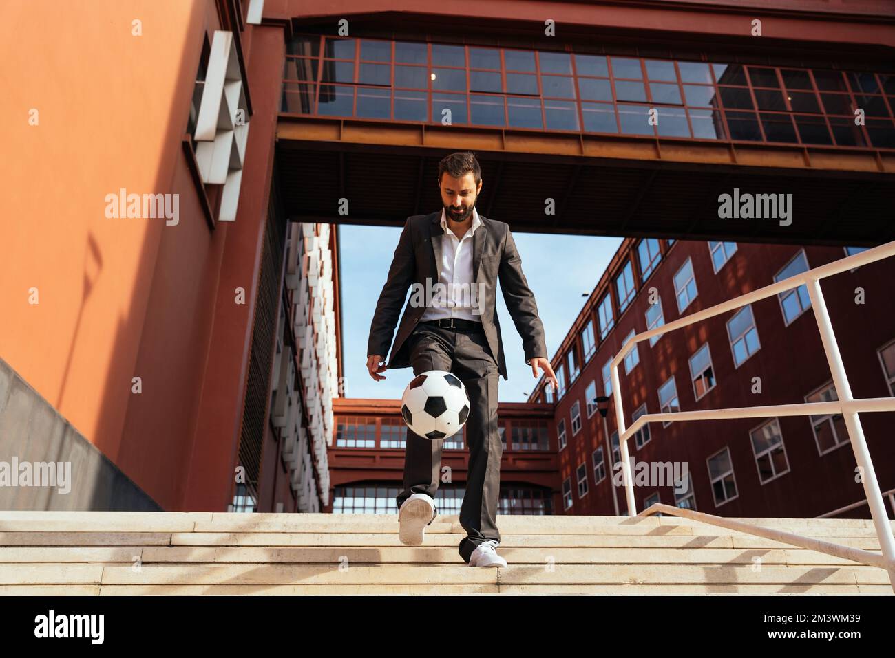 Bild eines Geschäftsmanns und Freispielers, der mit dem Ball auf der Straße Tricks macht. Konzept über Sport- und Geschäftsleute Stockfoto