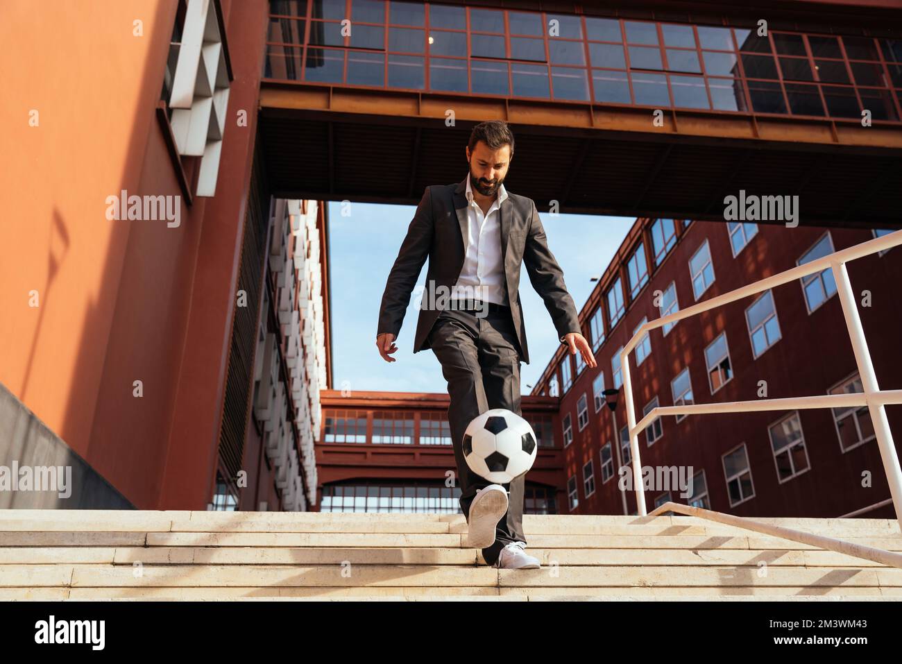 Bild eines Geschäftsmanns und Freispielers, der mit dem Ball auf der Straße Tricks macht. Konzept über Sport- und Geschäftsleute Stockfoto