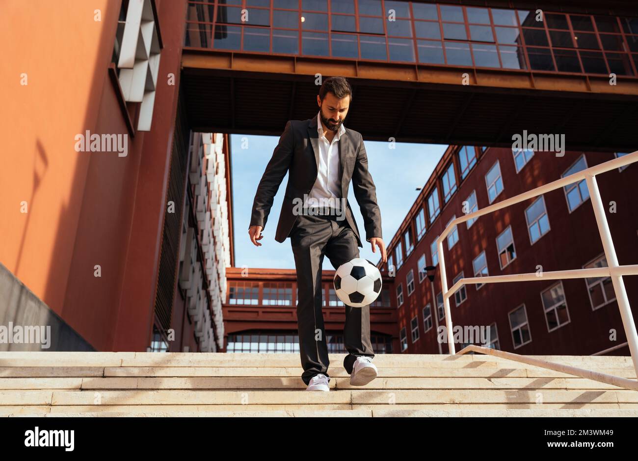 Bild eines Geschäftsmanns und Freispielers, der mit dem Ball auf der Straße Tricks macht. Konzept über Sport- und Geschäftsleute Stockfoto