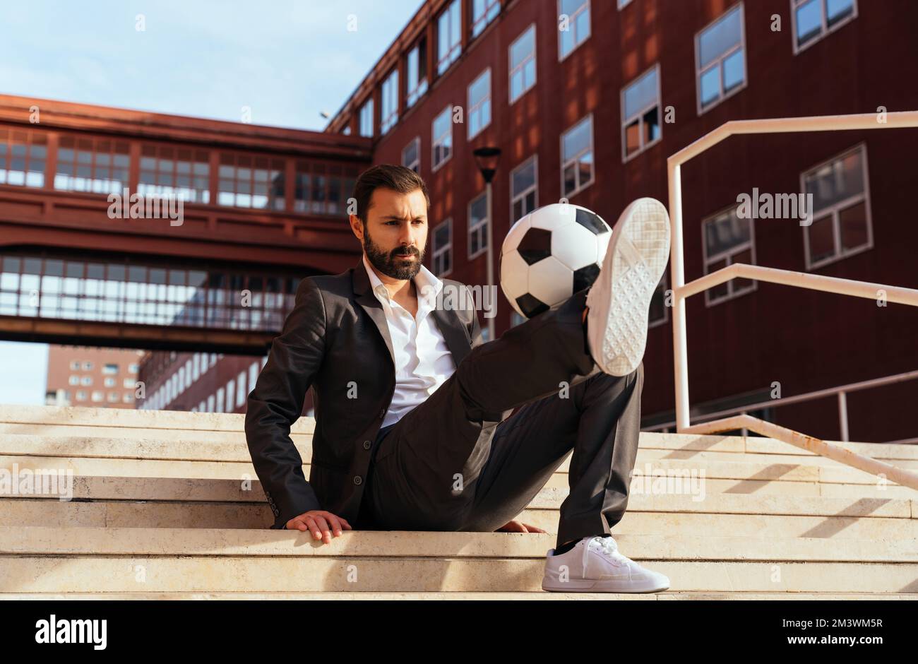 Bild eines Geschäftsmanns und Freispielers, der mit dem Ball auf der Straße Tricks macht. Konzept über Sport- und Geschäftsleute Stockfoto