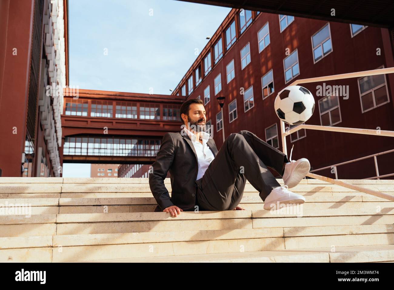 Bild eines Geschäftsmanns und Freispielers, der mit dem Ball auf der Straße Tricks macht. Konzept über Sport- und Geschäftsleute Stockfoto