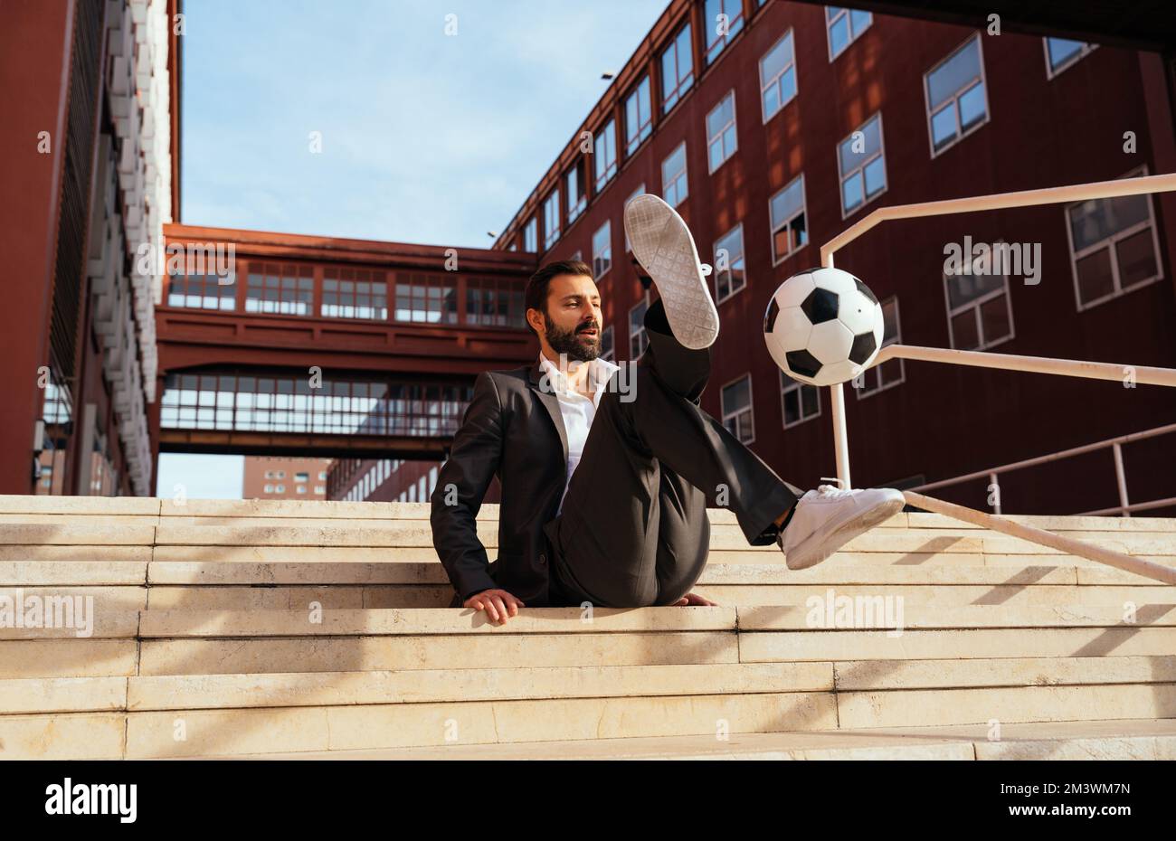 Bild eines Geschäftsmanns und Freispielers, der mit dem Ball auf der Straße Tricks macht. Konzept über Sport- und Geschäftsleute Stockfoto
