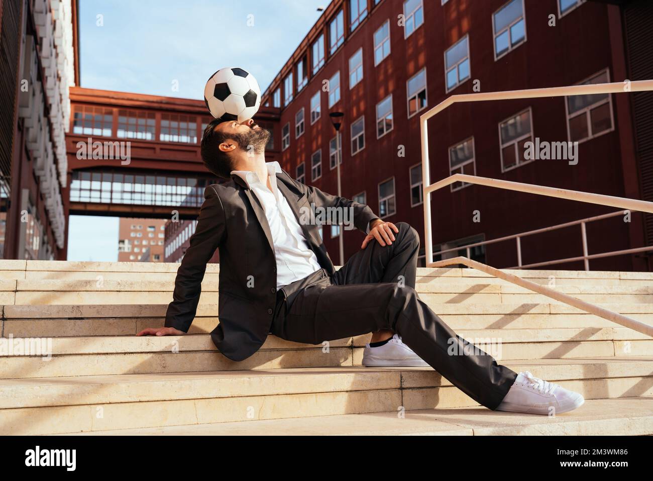 Bild eines Geschäftsmanns und Freispielers, der mit dem Ball auf der Straße Tricks macht. Konzept über Sport- und Geschäftsleute Stockfoto