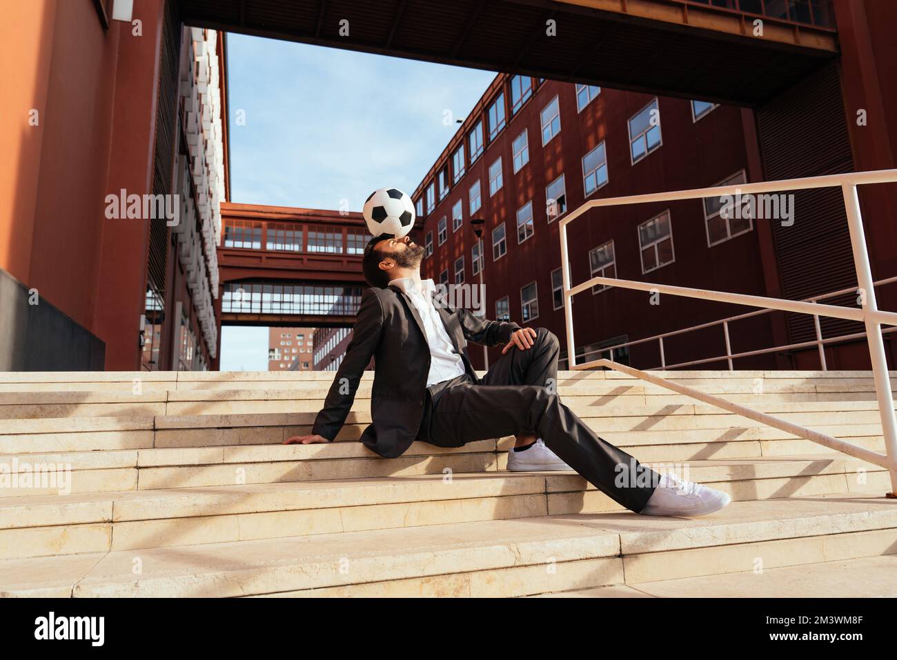 Bild eines Geschäftsmanns und Freispielers, der mit dem Ball auf der Straße Tricks macht. Konzept über Sport- und Geschäftsleute Stockfoto