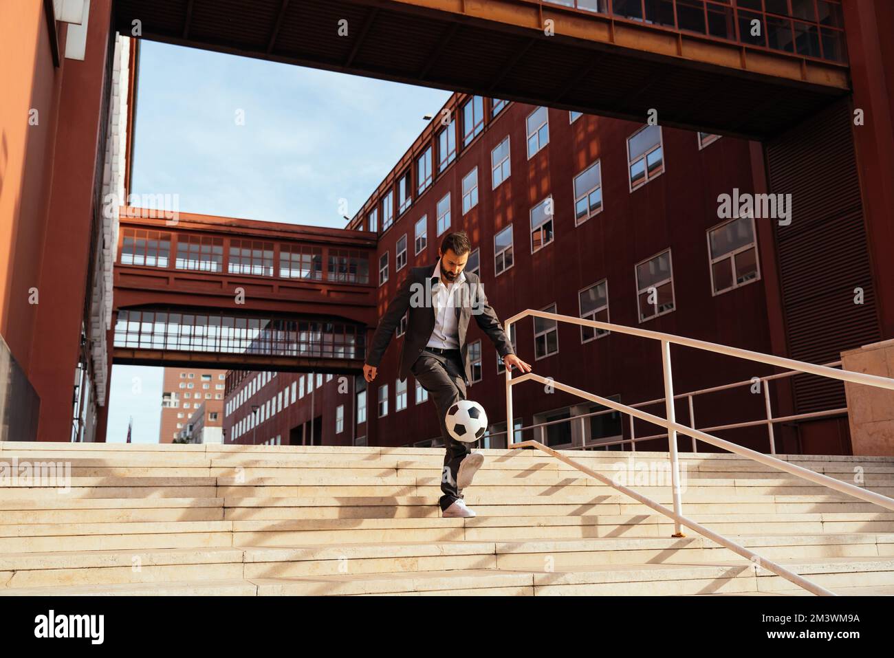 Bild eines Geschäftsmanns und Freispielers, der mit dem Ball auf der Straße Tricks macht. Konzept über Sport- und Geschäftsleute Stockfoto