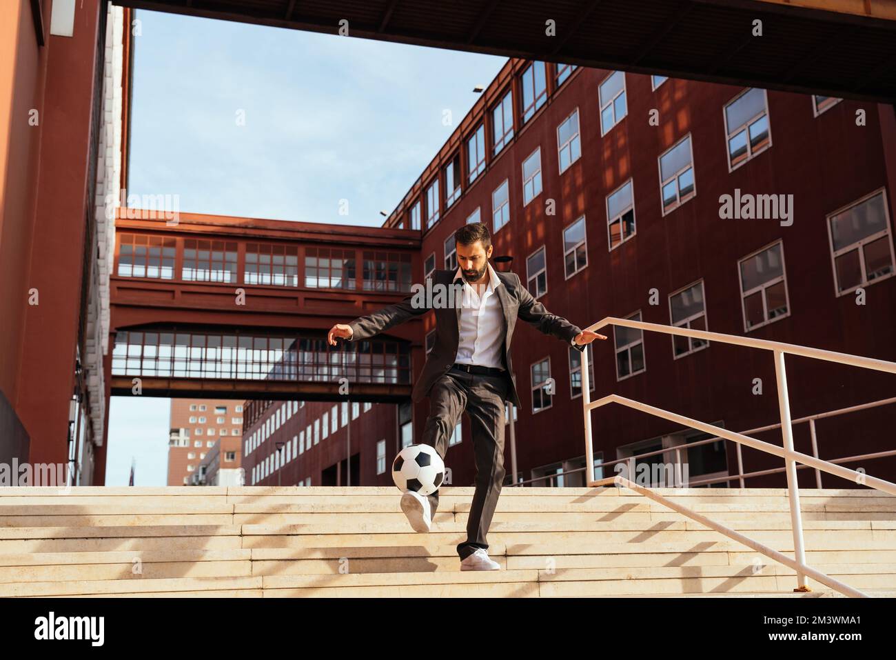 Bild eines Geschäftsmanns und Freispielers, der mit dem Ball auf der Straße Tricks macht. Konzept über Sport- und Geschäftsleute Stockfoto