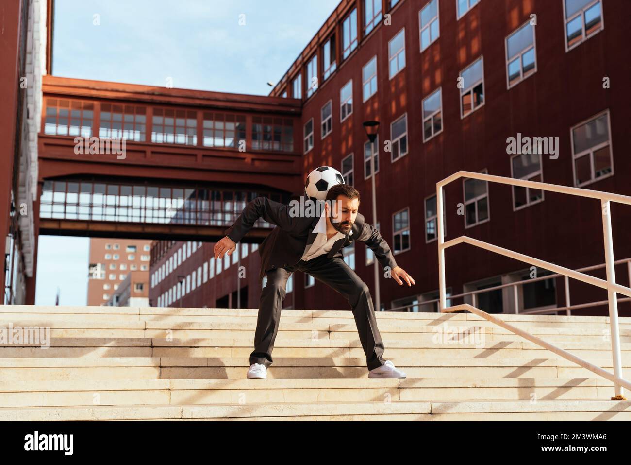 Bild eines Geschäftsmanns und Freispielers, der mit dem Ball auf der Straße Tricks macht. Konzept über Sport- und Geschäftsleute Stockfoto