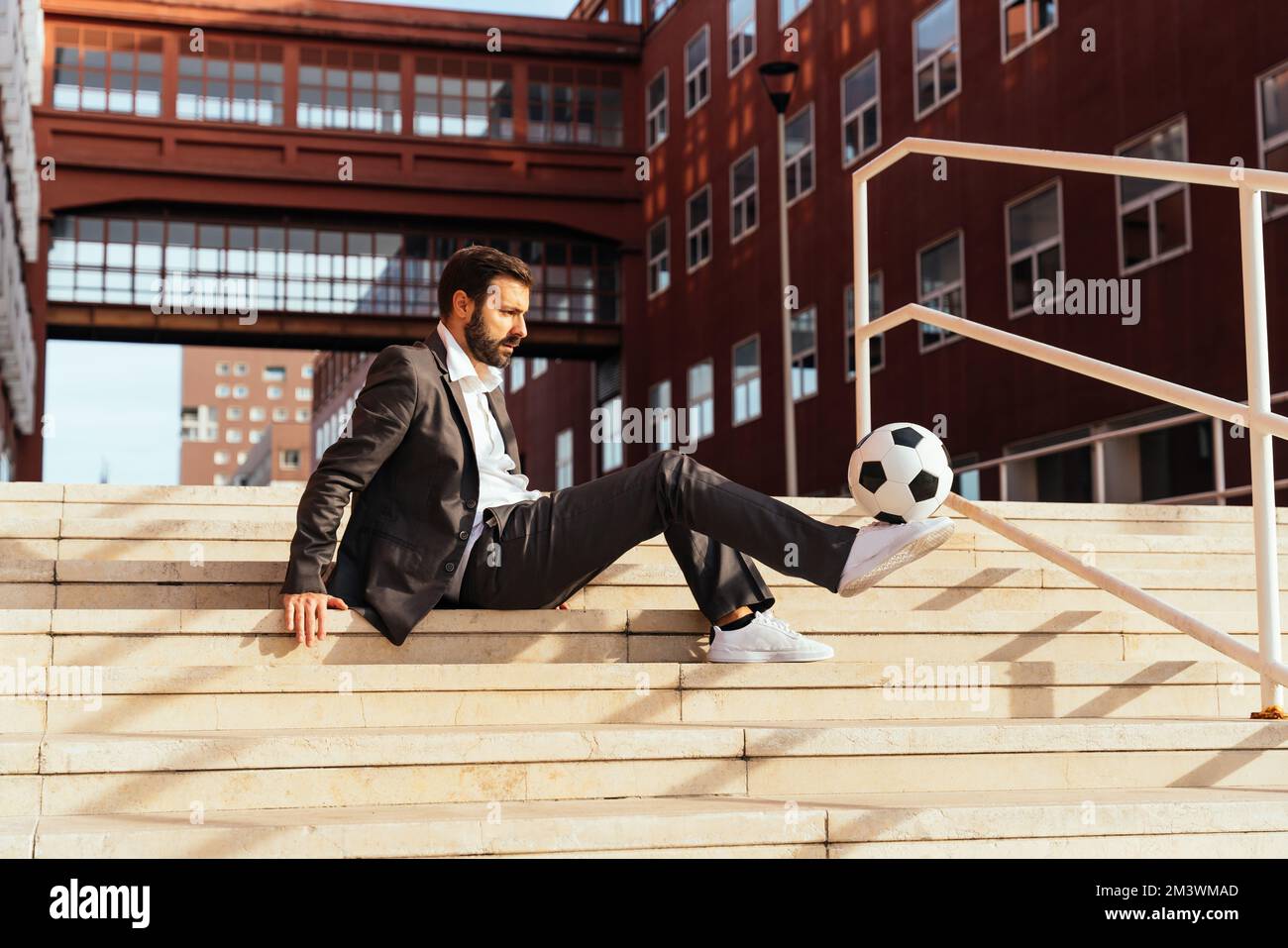 Bild eines Geschäftsmanns und Freispielers, der mit dem Ball auf der Straße Tricks macht. Konzept über Sport- und Geschäftsleute Stockfoto