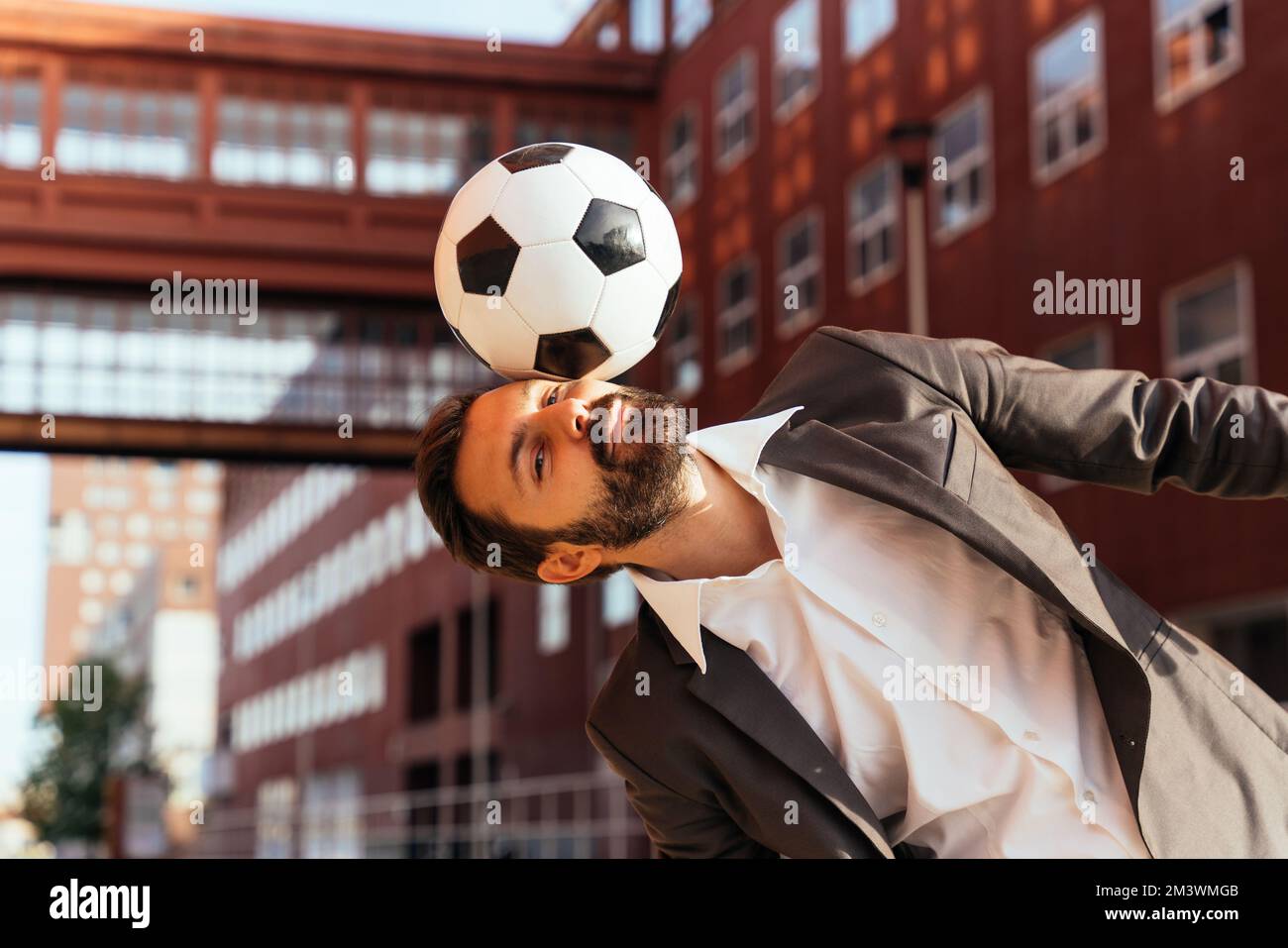 Bild eines Geschäftsmanns und Freispielers, der mit dem Ball auf der Straße Tricks macht. Konzept über Sport- und Geschäftsleute Stockfoto