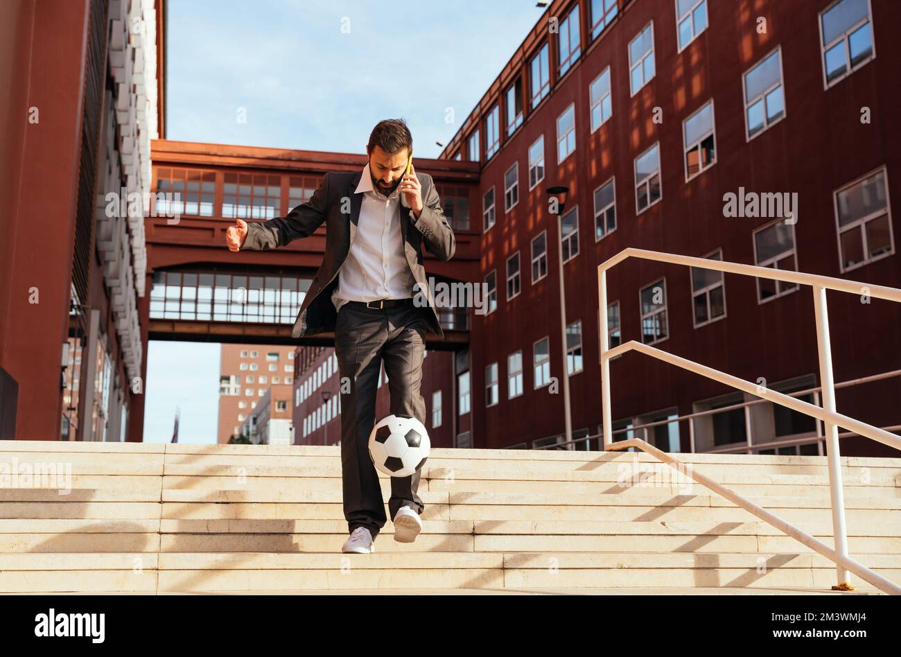 Bild eines Geschäftsmanns und Freispielers, der mit dem Ball auf der Straße Tricks macht. Konzept über Sport- und Geschäftsleute Stockfoto