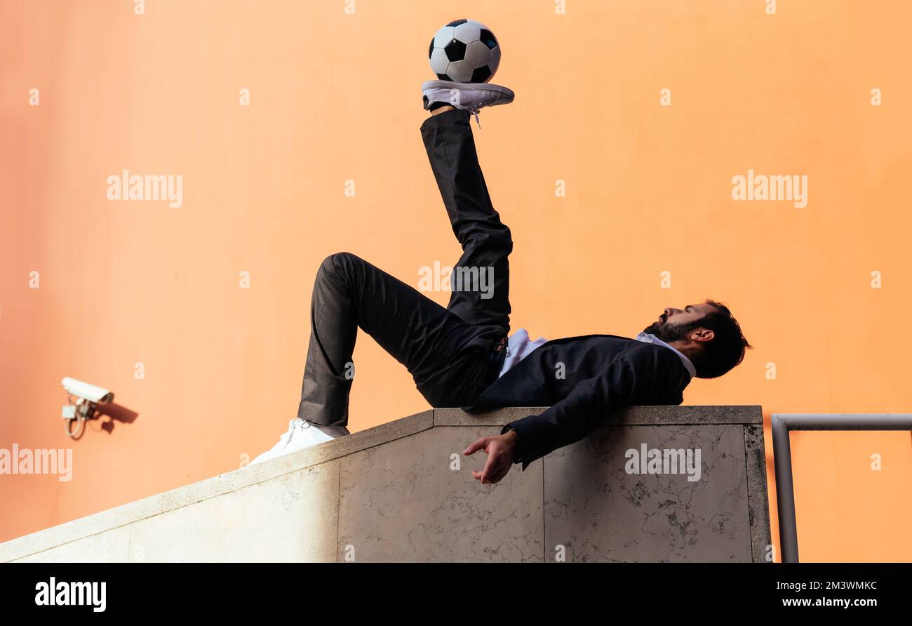 Bild eines Geschäftsmanns und Freispielers, der mit dem Ball auf der Straße Tricks macht. Konzept über Sport- und Geschäftsleute Stockfoto
