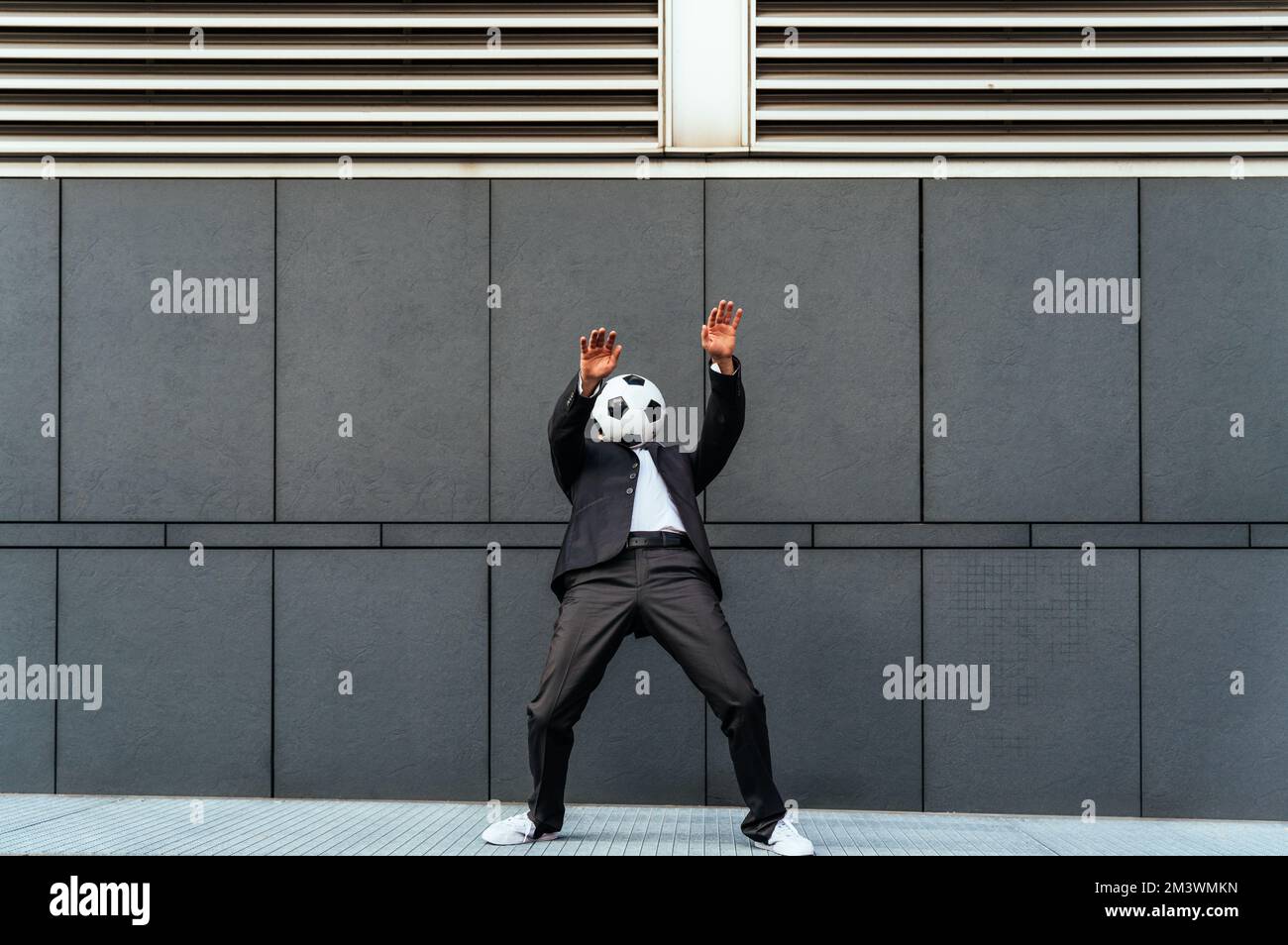 Bild eines Geschäftsmanns und Freispielers, der mit dem Ball auf der Straße Tricks macht. Konzept über Sport- und Geschäftsleute Stockfoto