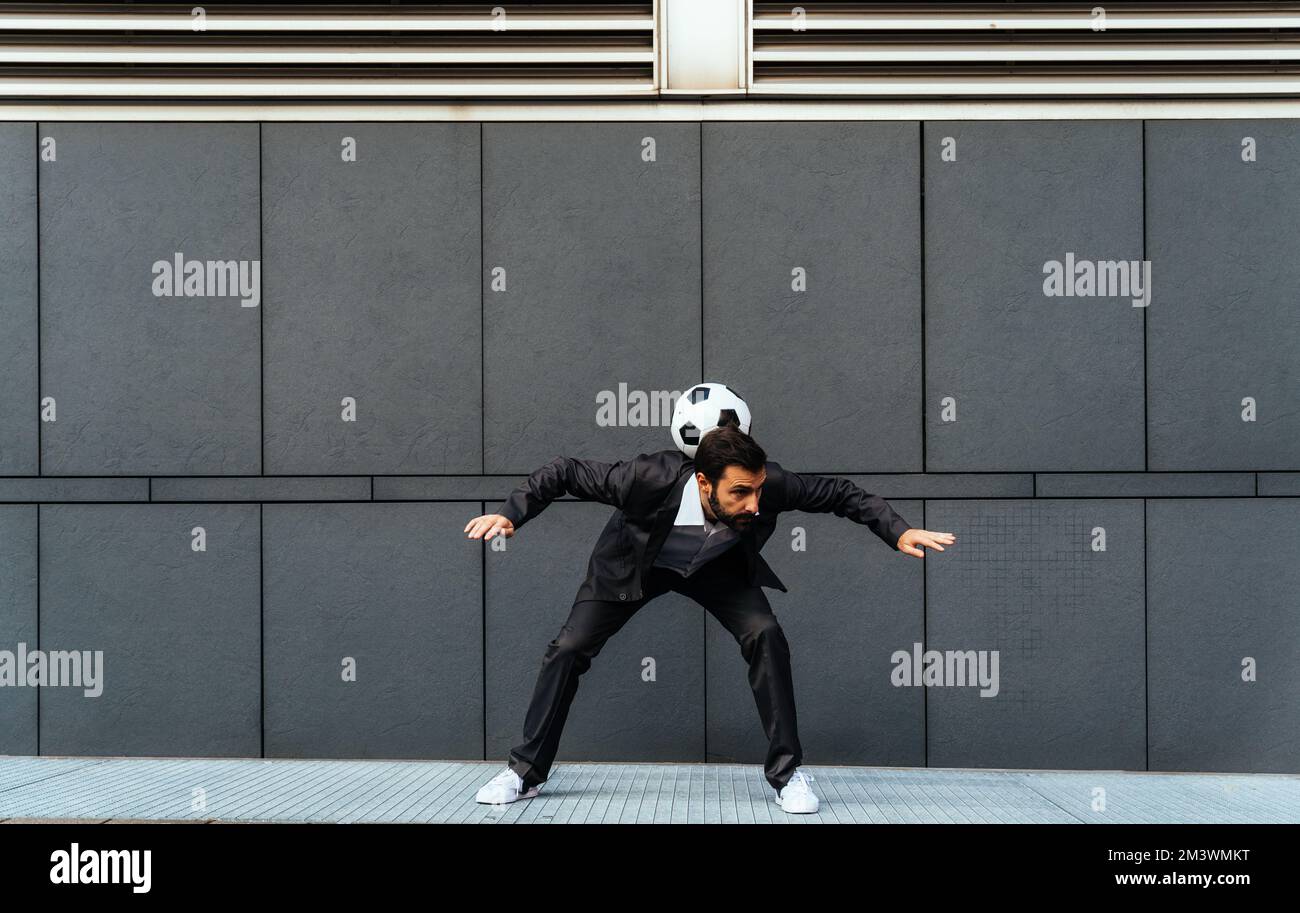 Bild eines Geschäftsmanns und Freispielers, der mit dem Ball auf der Straße Tricks macht. Konzept über Sport- und Geschäftsleute Stockfoto