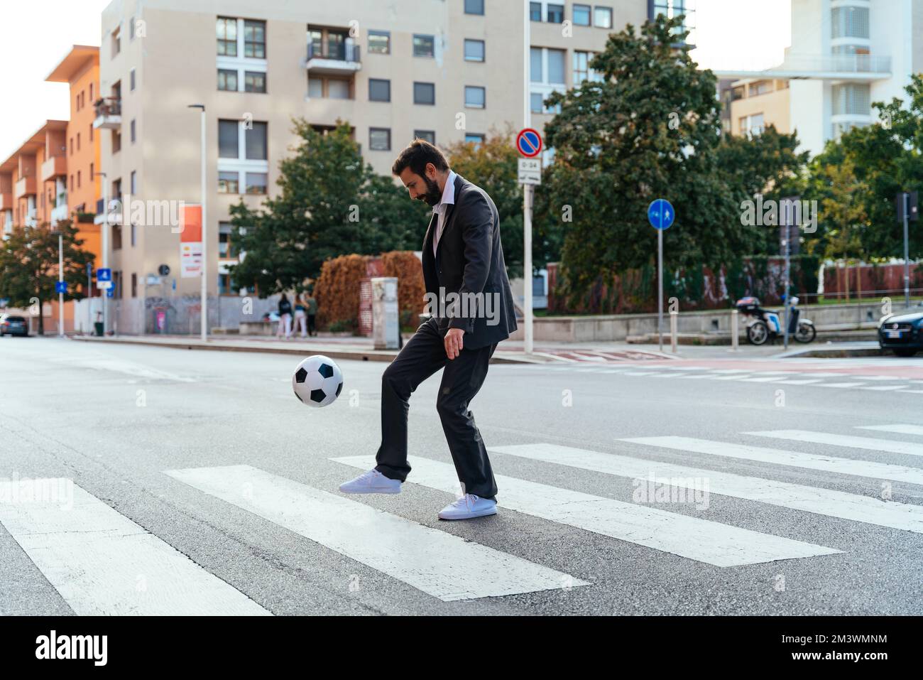 Bild eines Geschäftsmanns und Freispielers, der mit dem Ball auf der Straße Tricks macht. Konzept über Sport- und Geschäftsleute Stockfoto