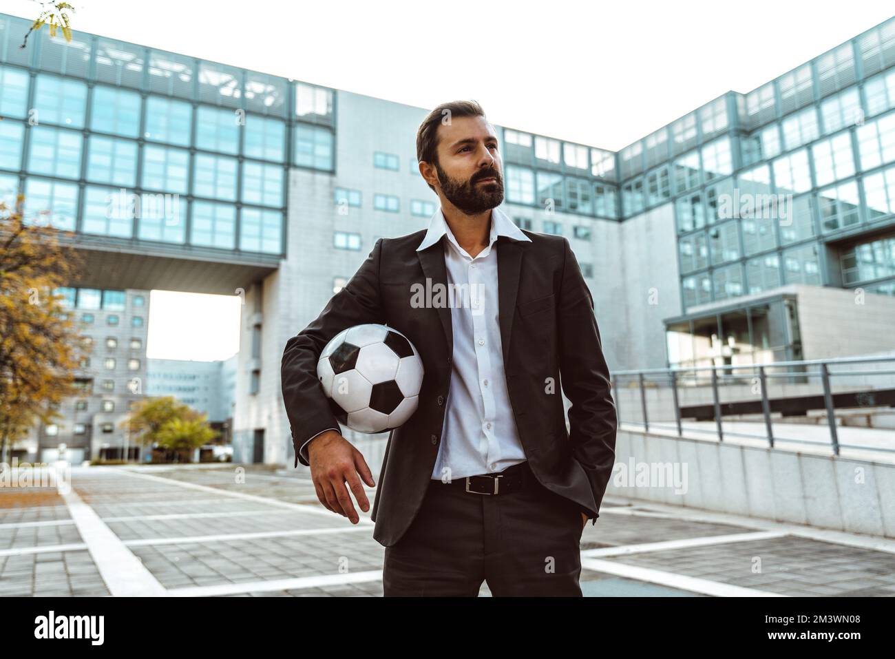 Bild eines Geschäftsmanns und Freispielers, der mit dem Ball auf der Straße Tricks macht. Konzept über Sport- und Geschäftsleute Stockfoto